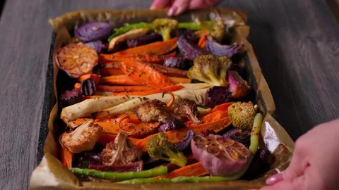 Hands Placing Roasted Vegetables Tray on Wooden Table for Sunday Roast Stock Footage 326321196