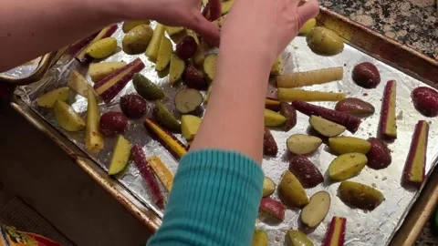 Hands placing root vegetables on the foil preparing for roasting Stockbeeldmateriaal 276384863