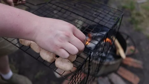 Hands placing sausages on a grill over glowing embers for a barbecue Stock Footage 337105164