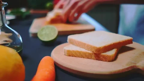 Hands placing toasted bread slices on a wooden cutting board in kitchen Vidéo 342844934