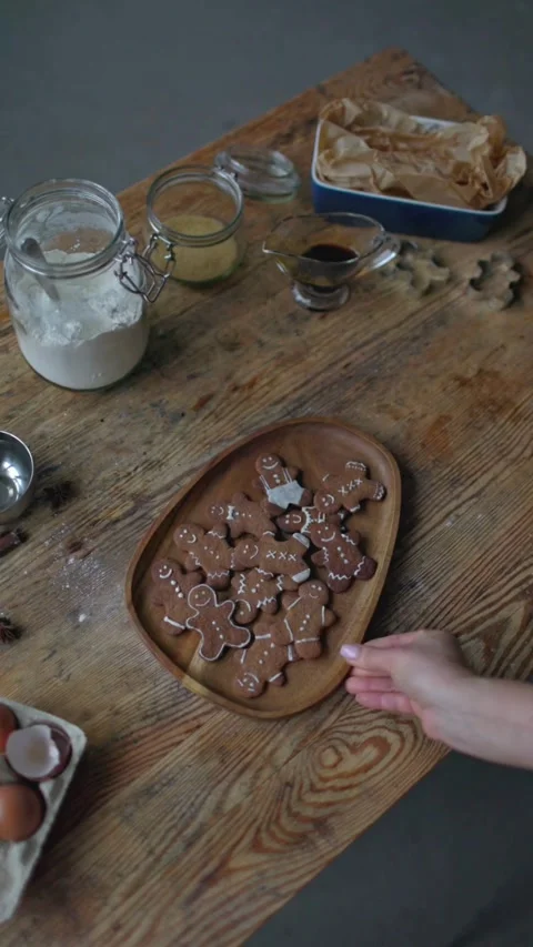 Hands placing tray of gingerbread cookies on wooden table Vídeos de archivo 331770059