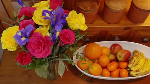 Hands placing a vase of flowers next to a bowl of fruit. Video stock 237861333