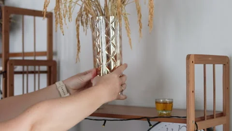 Hands placing a vase with wheat spikes on a shelf. Video stock 308724757