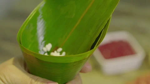 Hands Placing White Rice into Green Bamboo Leaf Cone for Asian Cuisine 库存影片 335501215