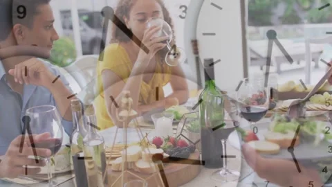 Hands plating salad, camera pulling back showing friends sharing meal, clock Stock Footage 334312676