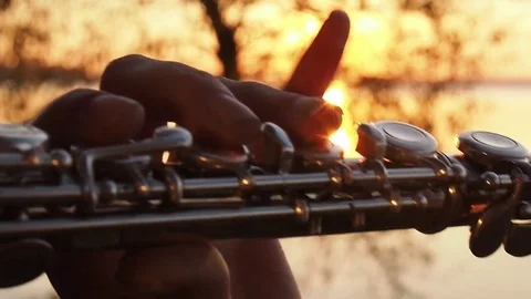 Hands Play the flute. Backlight rays of the sunset Stock-Footage 77467449