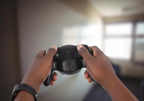 Hands playing with computer game controller with bright blurred background Stock Photos