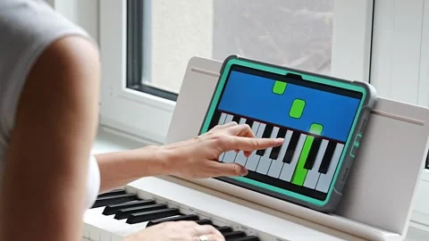 Hands playing a keyboard while following an interactive learning app on a tablet Stock Footage 303888523