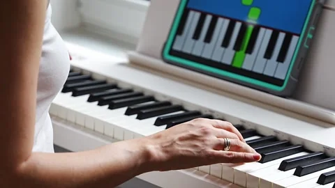 Hands playing a keyboard while following an interactive learning app on a tablet Stock Footage 303888999
