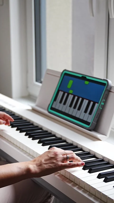Hands playing a keyboard while following an interactive learning app on a tablet Stock Footage 303889132