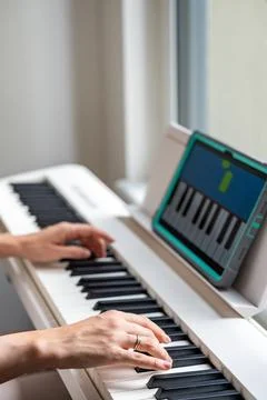 Hands playing a keyboard while following an interactive learning app on a tablet Stock Photos