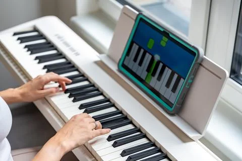 Hands playing a keyboard while following an interactive learning app on a tablet Stock Photos