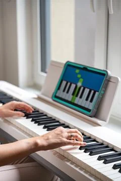Hands playing a keyboard while following an interactive learning app on a tablet Stock Photos