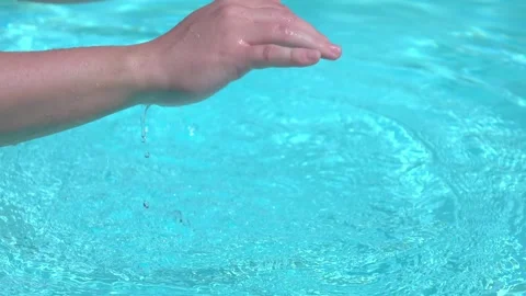 Hands playing with water in a pool, creating splashes in 4K Stock Footage 283460150