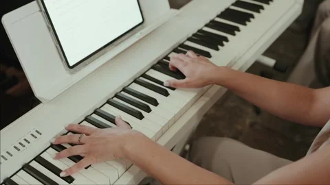 Hands Playing a White Digital Piano with a Tablet on the Music Stand Stock Footage 343697587