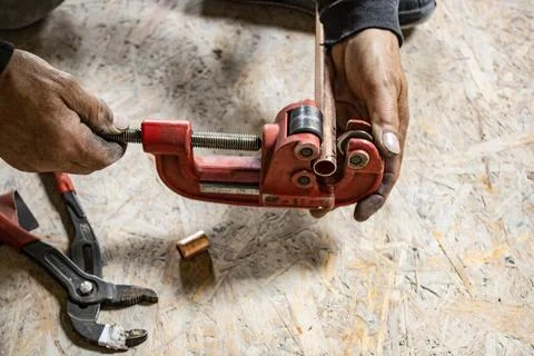 Hands of a plumber, copper pipe in a vice Stock Photos