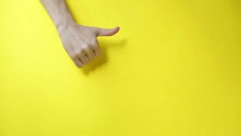 Hands point fingers to an empty space and show thumbs up. Yellow background.  Stock Footage 160089800