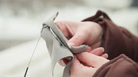Hands polishing silver bracelet with soft cloth outdoors, gently rubbing chain Stock Footage 345654478