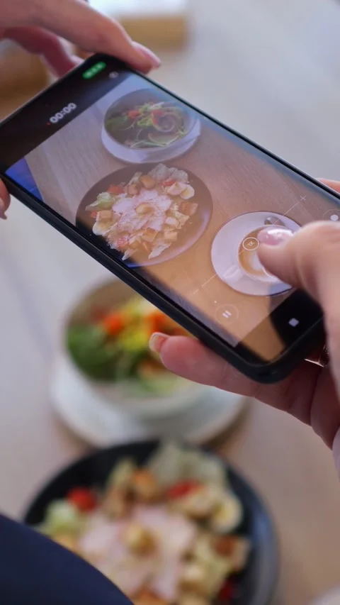 Hands position cellular phone over coffee shop breakfast to record food Stock Footage 346491300