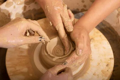 Hands of a potter, creating an earthen jar on the circle, top view Stock Photos