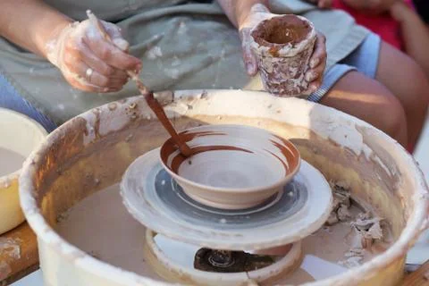 Hands of potter, creating an earthen jar on the circle, close-up Stock Photos