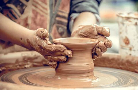 Hands of a potter at work. Potter making ceramic mug on the pottery wheel Stock Photos