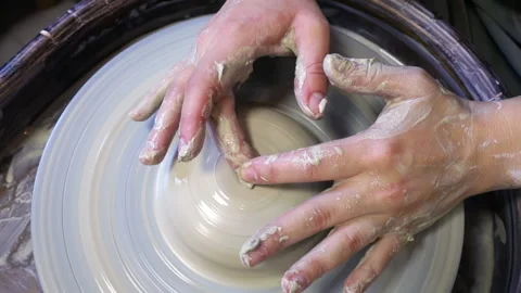 The hands of a potter's apprentice are trying to make a cup from a clay blank Stock-Footage 165554129