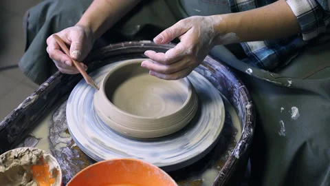 Hands of a potter's apprentice making a simple pattern on a clay cup blank Stock Footage 165554961