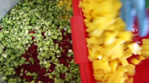 Hands pour chopped mango into a pot with pieces of different fruits in the food  Video stock 81012779