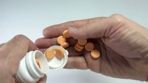 Hands pour orange-patterned vitamins onto palm in 4K Stock Footage 142958981