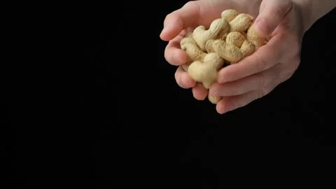 Hands pour unpeeled peanuts in the shell, black background. space for text, slow Video stock 306054884