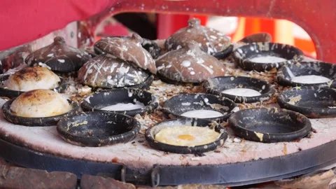 Hands pouring batter into round molds on a hot griddle while small cakes bake. S 스톡 동영상 339279925