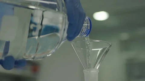 Hands pouring a clear fluid from the bottle to capacity bottle Stock-Footage 153474996