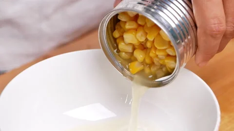 Hands pouring corn kernels in metal can into a bowl, corns canned goods. Stock Footage 158658222