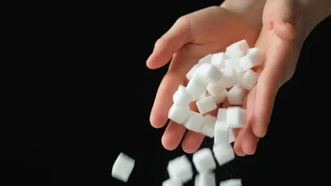 Hands pouring cubes of white pressed beetroot refined sugar, black background Stock Footage 295121175