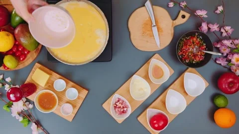 Hands Pouring Egg Mixture into Frying Pan in Indoor Kitchen Stock Footage 342836463
