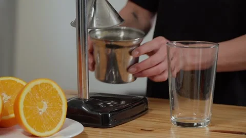 Hands pouring freshly squeezed orange juice into a glass glass Stock Footage 241994168