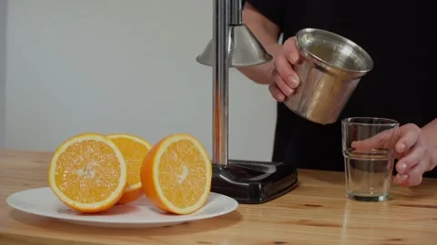 Hands pouring freshly squeezed orange juice into a glass glass Stock-Footage 241994279