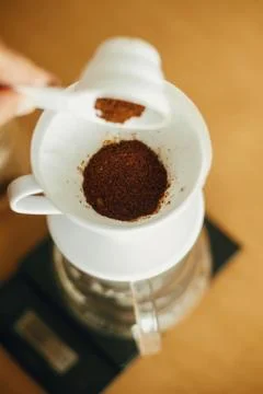 Hands pouring grounded coffee in filter. Preparing for alternative coffee bre Stock Photos