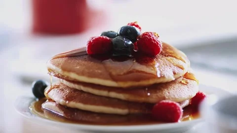 Hands Pouring Maple Syrup Onto a Stack Of Pancakes With fresh berries. Stock-Footage 336589011