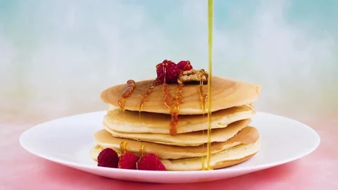 Hands Pouring Maple Syrup Onto a Stack Of Pancakes With fresh berries. 스톡 동영상 336589094