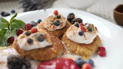 Hands Pouring Maple Syrup Onto a Stack Of Pancakes With fresh berries. Stock-Footage 336589107