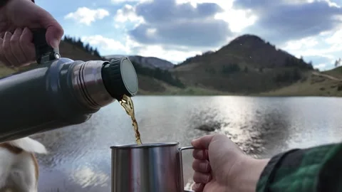 Hands pouring tea from a thermos into a cup. Stock Footage 317629874