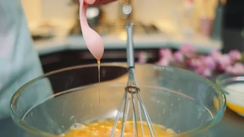 Hands pouring vanilla extract into egg mixture in kitchen Stockbeeldmateriaal 342880131