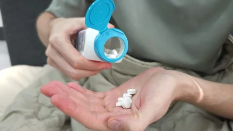 Hands pouring white tablets from bottle into palm. Stock Footage 284044996