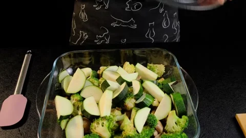 Hands Pouring Zucchini Slices into Baking Dish with Broccoli and Mushrooms, Video stock 341433282