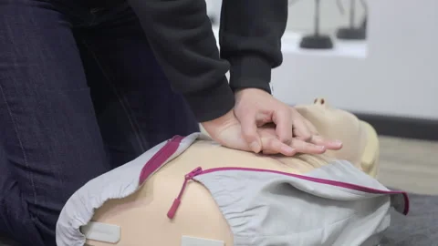 Hands practicing CPR chest compressions on dummy, first aid training session Stock Footage 308494370