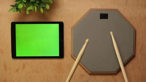 Hands practicing drumming on a pad with a tablet showing green screen Vidéo 341737708