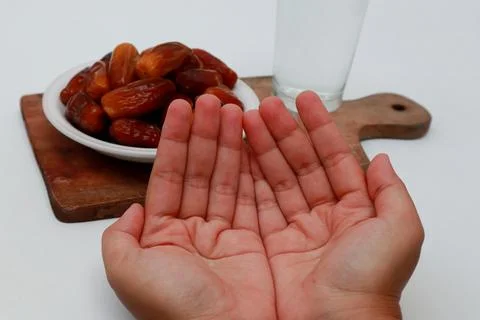 Hands with a prayer gesture against the background A plate of dates, a glas.. Stock Photos