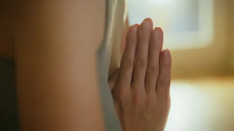 Hands in prayer position during a quiet moment of reflection in a serene ind Vídeo Stock 299036231
